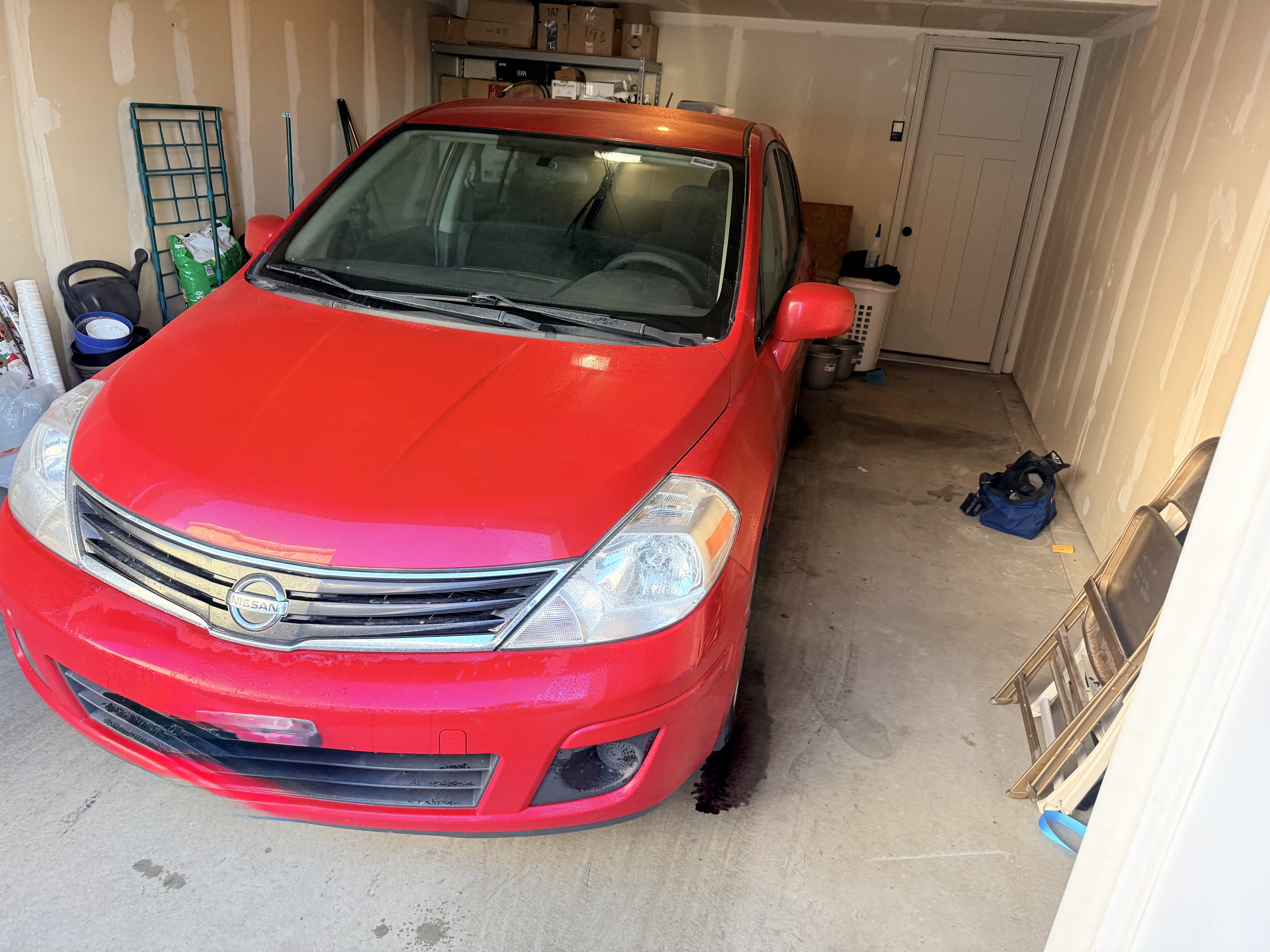 Red Nissan Versa before wash - front view covered in dust and grime