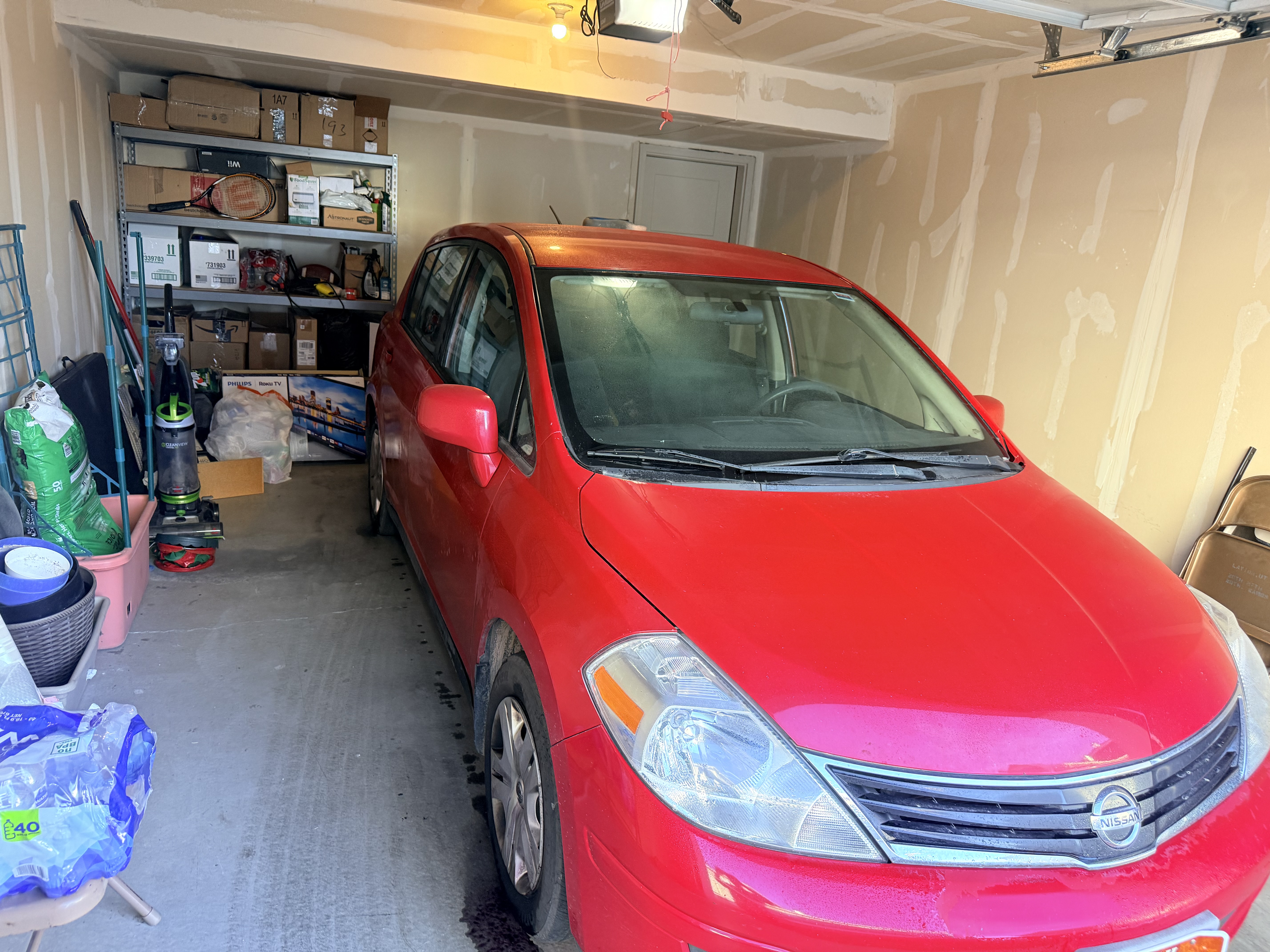 Red Nissan Versa before wash - side profile in garage