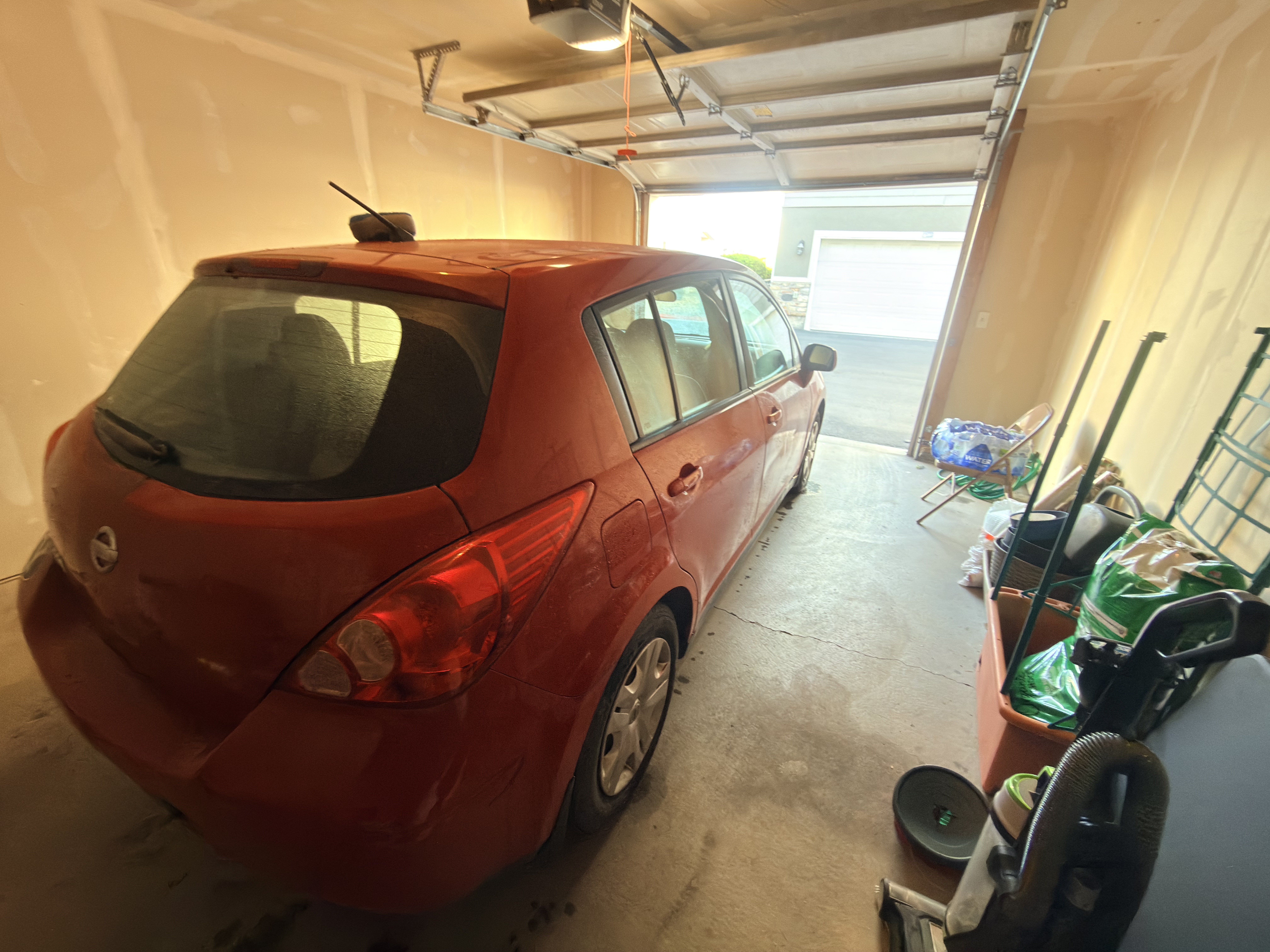 Red Nissan Versa before wash - rear three-quarter view